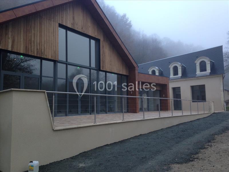 Bâtiment moderne avec façade en bois, grandes baies vitrées et terrasse, entouré de brouillard.