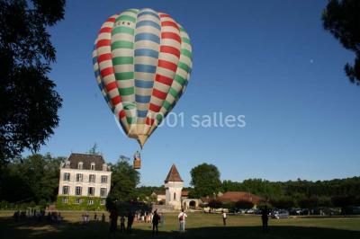 Vue aérienne de plusieurs bus stationnés près d'un bâtiment ancien, entourés de groupes de personnes et de verdure.