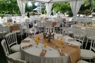 Vue aérienne de plusieurs bus stationnés près d'un bâtiment ancien, entourés de groupes de personnes et de verdure.