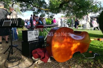 Vue aérienne de plusieurs bus stationnés près d'un bâtiment ancien, entourés de groupes de personnes et de verdure.