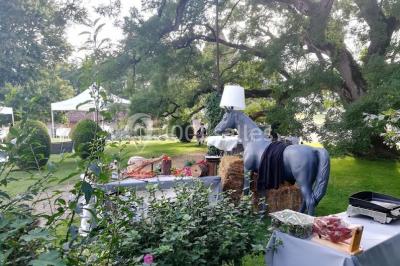 Vue aérienne de plusieurs bus stationnés près d'un bâtiment ancien, entourés de groupes de personnes et de verdure.