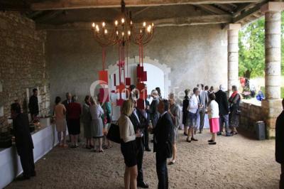 Vue aérienne de plusieurs bus stationnés près d'un bâtiment ancien, entourés de groupes de personnes et de verdure.