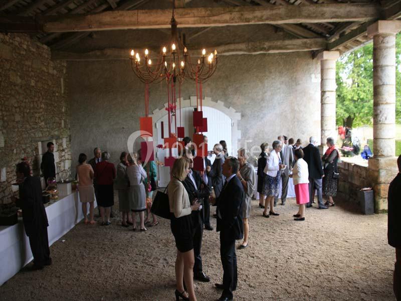 Groupe de personnes discutant sous un auvent en pierre, avec un buffet et une décoration colorée en arrière-plan.