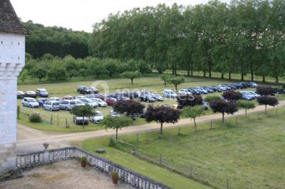 Vue aérienne de plusieurs bus stationnés près d'un bâtiment ancien, entourés de groupes de personnes et de verdure.