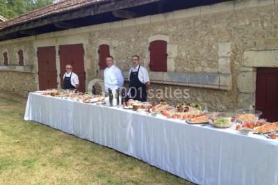 Vue aérienne de plusieurs bus stationnés près d'un bâtiment ancien, entourés de groupes de personnes et de verdure.