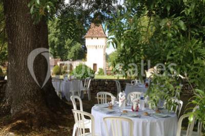 Vue aérienne de plusieurs bus stationnés près d'un bâtiment ancien, entourés de groupes de personnes et de verdure.