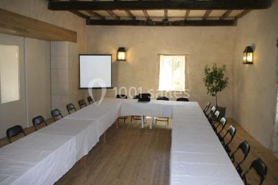 Vue aérienne de plusieurs bus stationnés près d'un bâtiment ancien, entourés de groupes de personnes et de verdure.