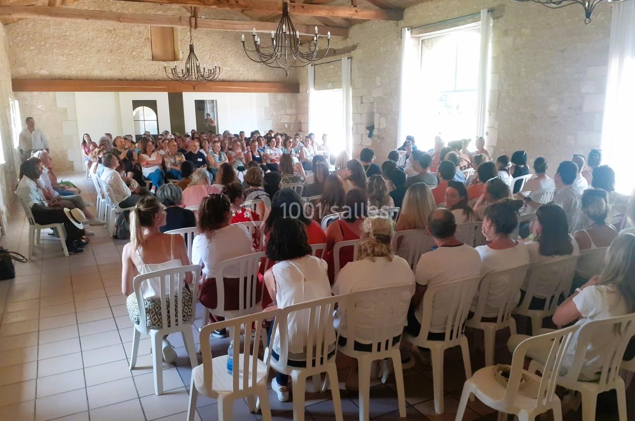 Un groupe de personnes assises dans une salle lumineuse en pierre, participant à une réunion ou une conférence.