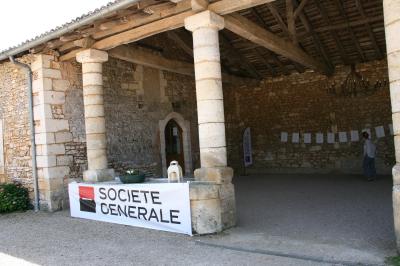 Vue aérienne de plusieurs bus stationnés près d'un bâtiment ancien, entourés de groupes de personnes et de verdure.