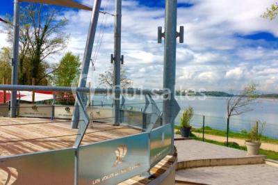Chambre en bois avec un lit double, une fenêtre, un éclairage mural et une porte fermée.