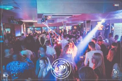 Chambre en bois avec un lit double, une fenêtre, un éclairage mural et une porte fermée.