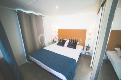 Chambre en bois avec un lit double, une fenêtre, un éclairage mural et une porte fermée.