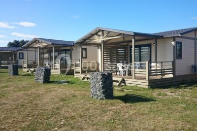 Chambre en bois avec un lit double, une fenêtre, un éclairage mural et une porte fermée.