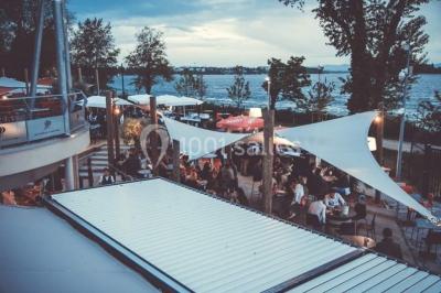 Foule dans une discothèque éclairée par des lumières bleues, avec une ambiance festive et un panneau lumineux au premier…