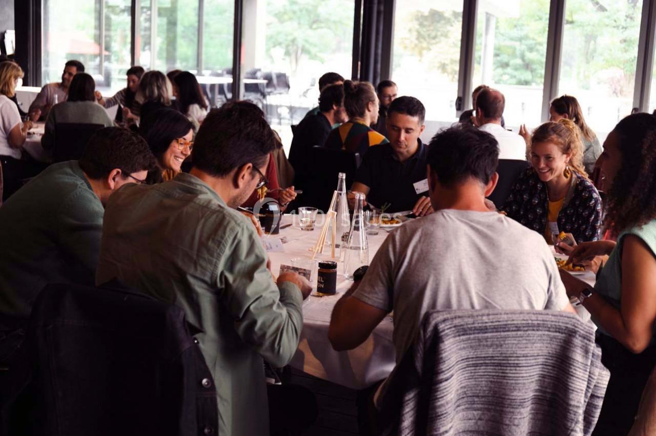 Un groupe de personnes partage un repas autour d'une grande table dans un restaurant lumineux.