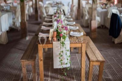 Dortoir sous combles avec murs en pierre, matelas au sol alignés et poutres apparentes.