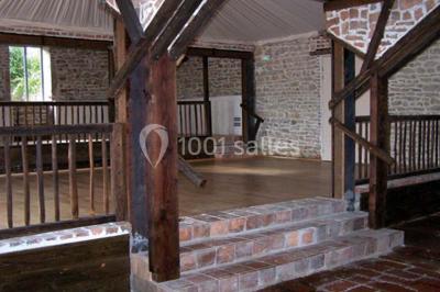 Dortoir sous combles avec murs en pierre, matelas au sol alignés et poutres apparentes.