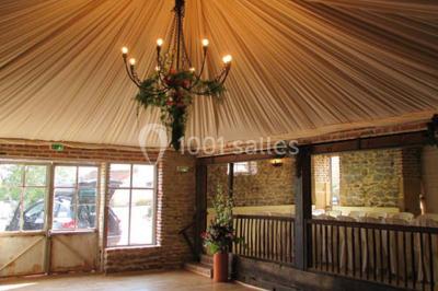 Dortoir sous combles avec murs en pierre, matelas au sol alignés et poutres apparentes.