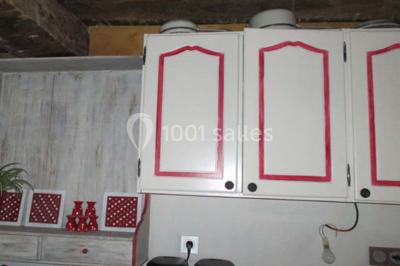 Dortoir sous combles avec murs en pierre, matelas au sol alignés et poutres apparentes.