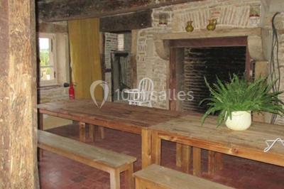 Dortoir sous combles avec murs en pierre, matelas au sol alignés et poutres apparentes.