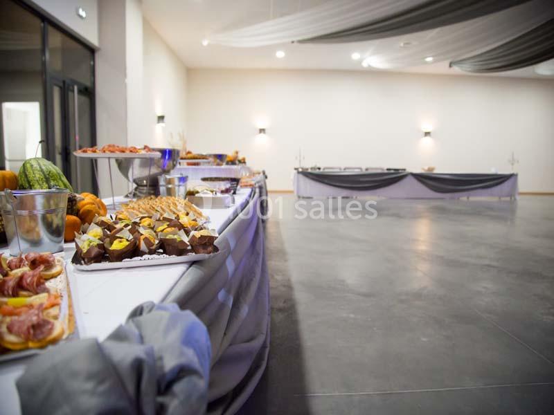 Buffet varié disposé sur une longue table dans une grande salle lumineuse avec décoration sobre.