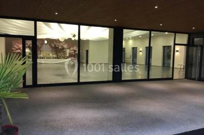 Parking vide avec marquages au sol, situé devant un bâtiment en bois entouré d'arbres et de montagnes.