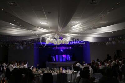 Parking vide avec marquages au sol, situé devant un bâtiment en bois entouré d'arbres et de montagnes.