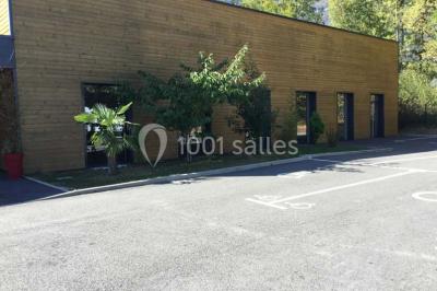 Parking vide avec marquages au sol, situé devant un bâtiment en bois entouré d'arbres et de montagnes.