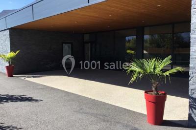 Parking vide avec marquages au sol, situé devant un bâtiment en bois entouré d'arbres et de montagnes.