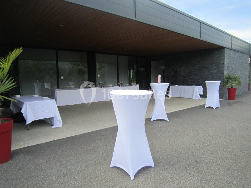 Tables hautes et buffets dressés sous un auvent moderne, prêts pour un événement en extérieur.