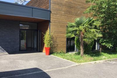 Parking vide avec marquages au sol, situé devant un bâtiment en bois entouré d'arbres et de montagnes.