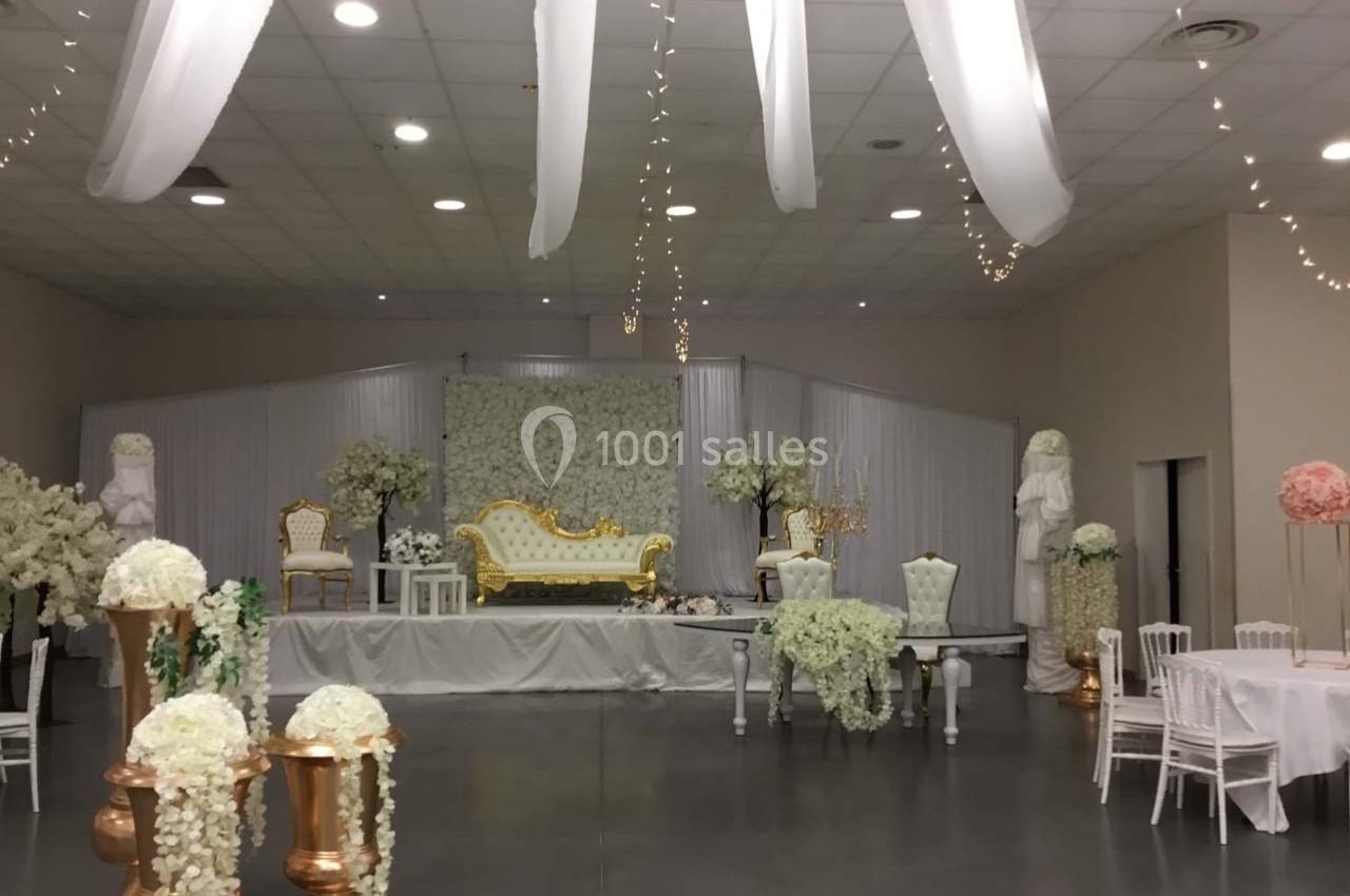 Salle de réception décorée avec des fleurs blanches, des statues, un canapé doré et des chaises élégantes.
