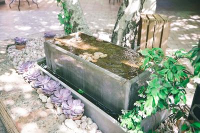 Salle de réception avec tables rondes dressées, nappes blanches, chaises en bois et décoration florale.