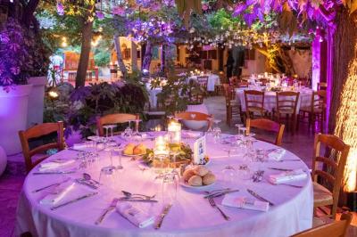 Salle de réception avec tables rondes dressées, nappes blanches, chaises en bois et décoration florale.