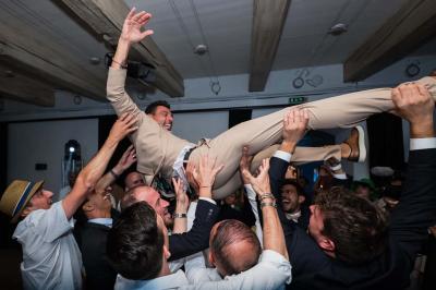 Salle de réception avec tables rondes dressées, nappes blanches, chaises en bois et décoration florale.