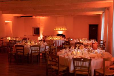 Salle de réception avec tables rondes dressées, nappes blanches, chaises en bois et décoration florale.