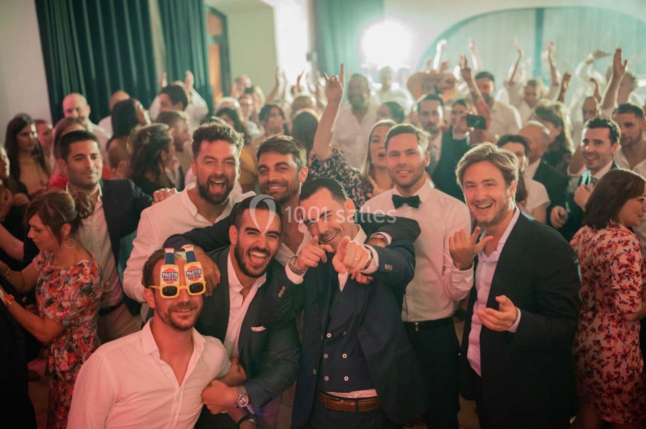 Un groupe de personnes souriantes posant lors d'une fête animée, entouré d'une foule festive en arrière-plan.