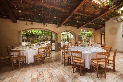 Salle de réception avec tables rondes dressées, nappes blanches, chaises en bois et décoration florale.