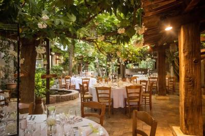 Salle de réception avec tables rondes dressées, nappes blanches, chaises en bois et décoration florale.