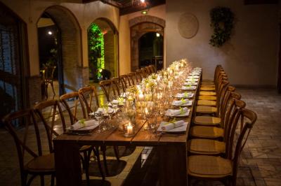 Salle de réception avec tables rondes dressées, nappes blanches, chaises en bois et décoration florale.