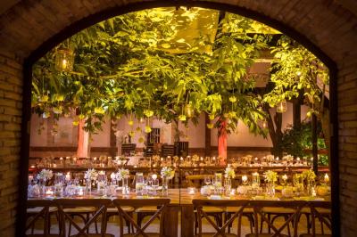 Salle de réception avec tables rondes dressées, nappes blanches, chaises en bois et décoration florale.