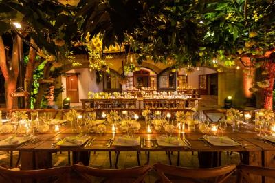 Salle de réception avec tables rondes dressées, nappes blanches, chaises en bois et décoration florale.