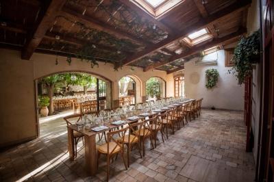 Salle de réception avec tables rondes dressées, nappes blanches, chaises en bois et décoration florale.