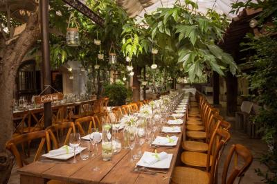Salle de réception avec tables rondes dressées, nappes blanches, chaises en bois et décoration florale.
