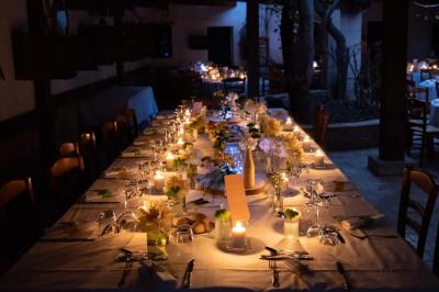 Salle de réception avec tables rondes dressées, nappes blanches, chaises en bois et décoration florale.