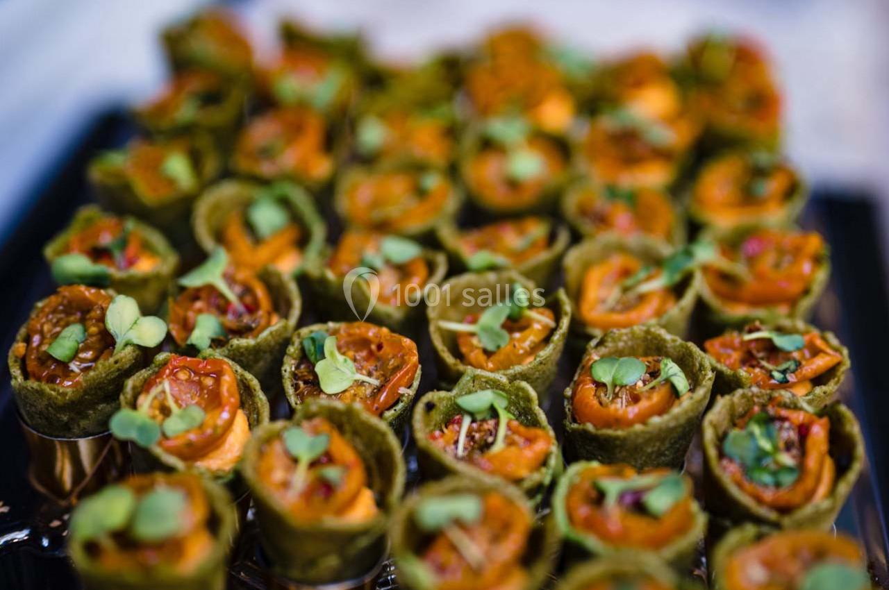 Petits roulés végétariens garnis de légumes colorés et décorés de jeunes pousses, présentés sur un plateau.