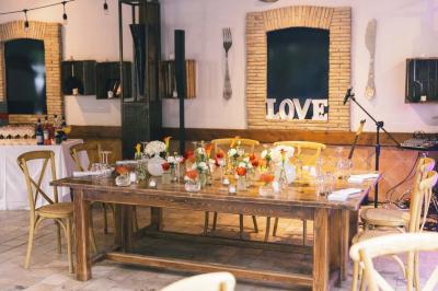 Salle de réception avec tables rondes dressées, nappes blanches, chaises en bois et décoration florale.