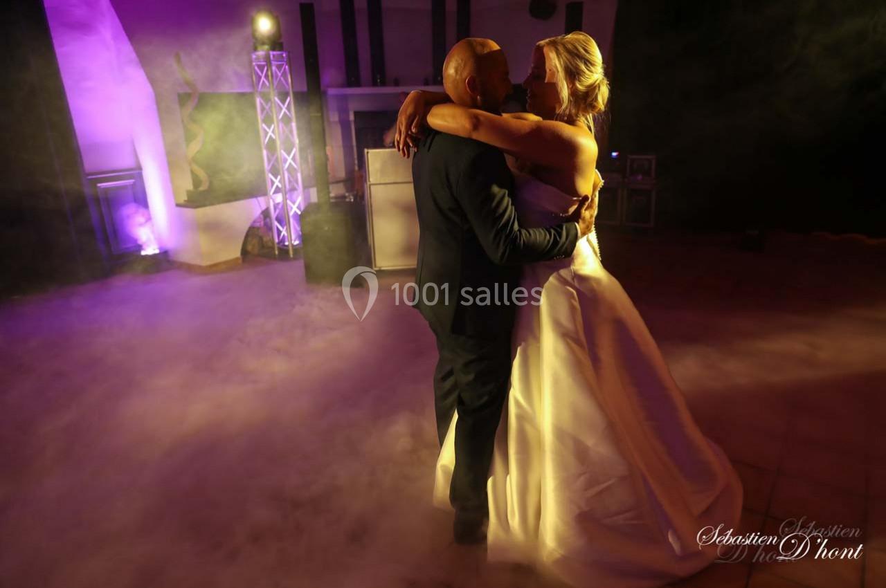 Un couple danse dans une ambiance tamisée avec éclairage violet et fumée au sol.