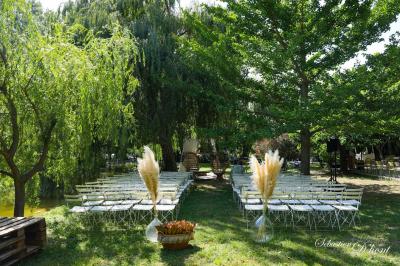 Salle de réception avec tables rondes dressées, nappes blanches, chaises en bois et décoration florale.