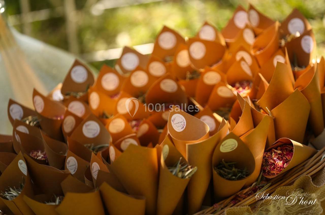 Cônes en papier kraft remplis de pétales colorés disposés sur une table en extérieur.